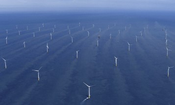 Image of rows of wind turbines located in the blue ocean.